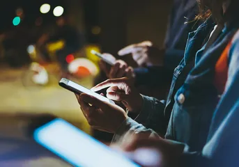 Close shot of people’s hands scrolling through their smartphones symbolizing safe online usage.