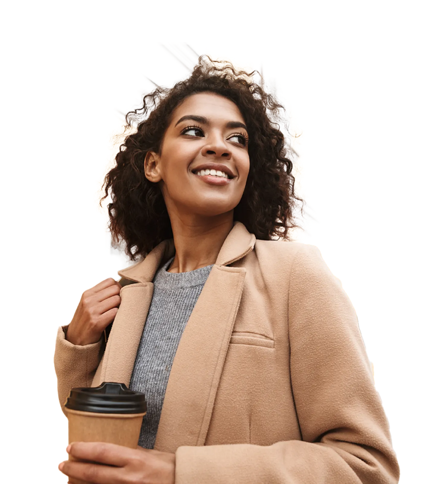 Cheerful young woman wearing a winter coat and walking outdoors while holding a coffee cup in her left hand.