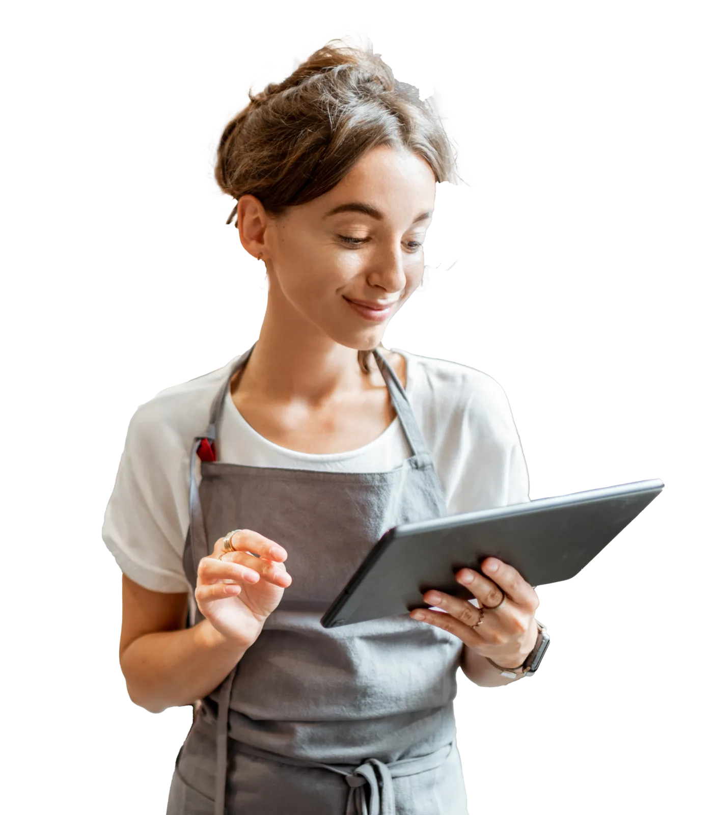A young woman wearing an apron and using a tablet at a small café. 