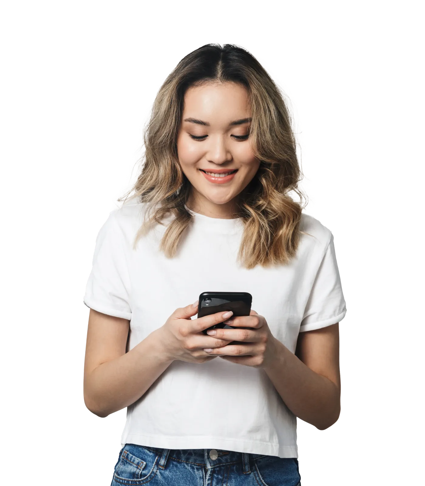 A young woman standing and smiling while looking down at her smartphone.